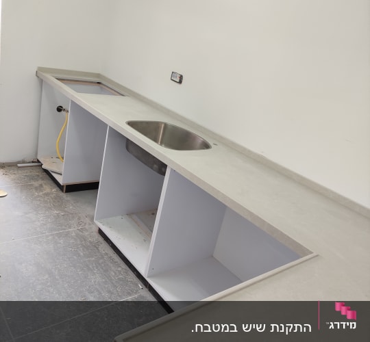 משטח שיש בהיר למטבח עם כיור נירוסטה מותקן וקנט אחורי